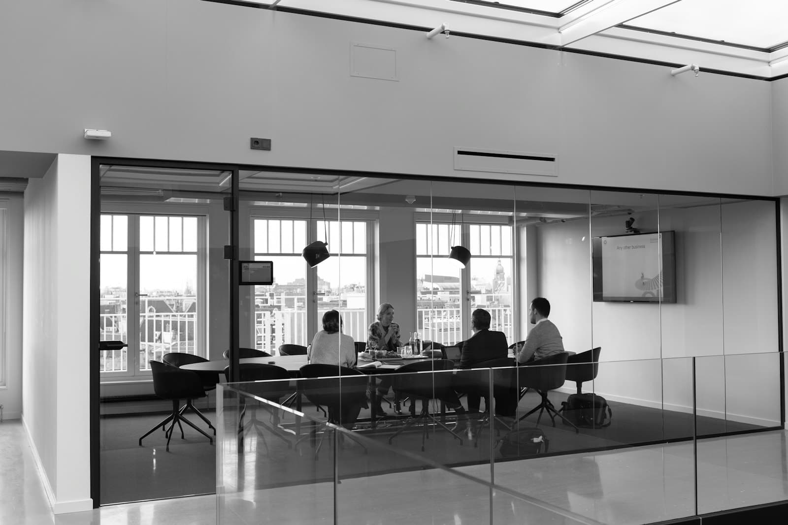 A glass-walled meeting room with a wall display