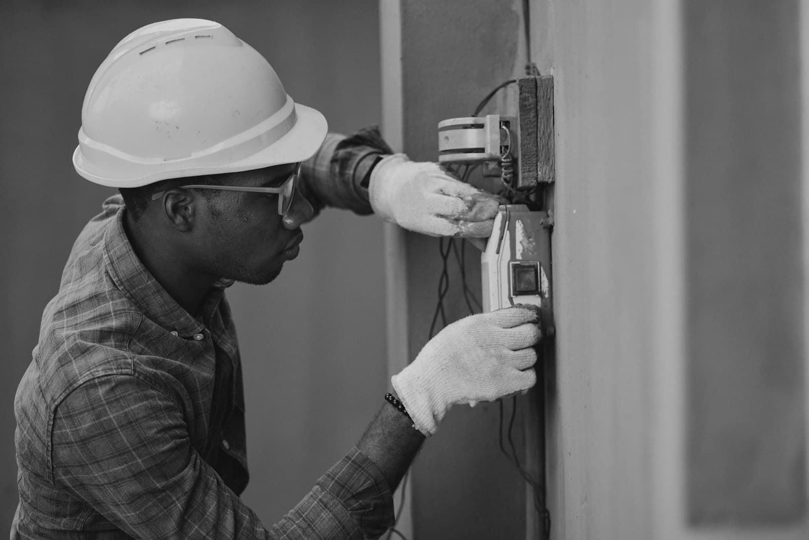 An installer in a hard hat working on wall wiring