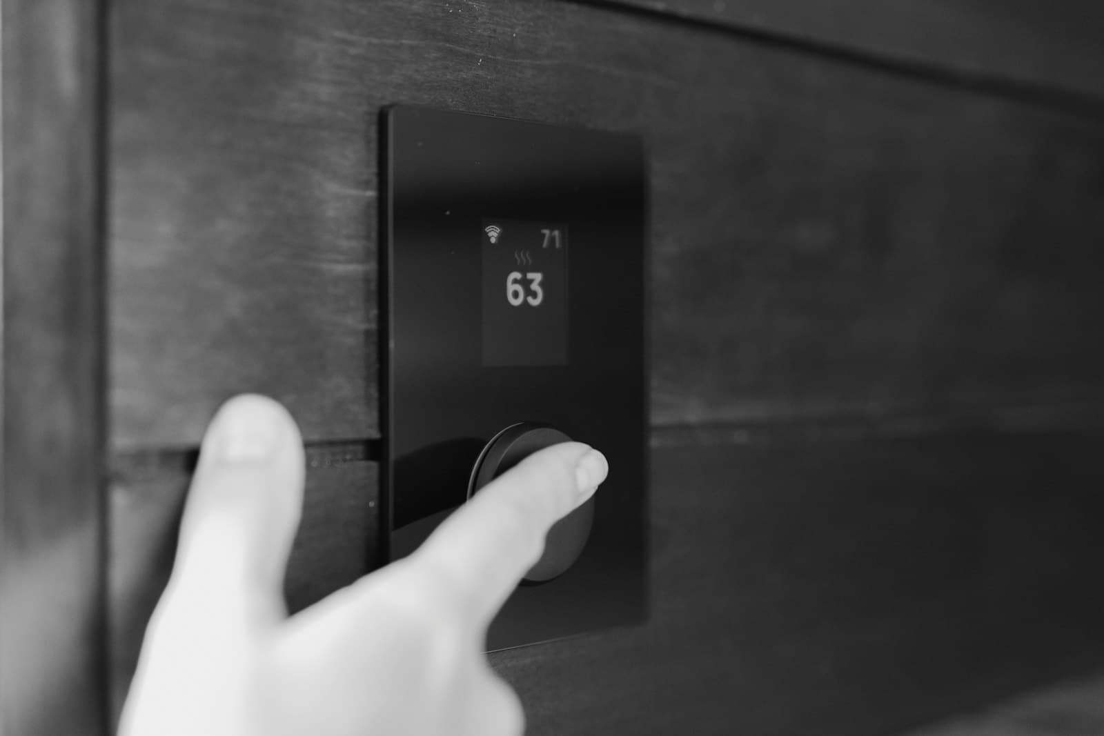 A hand adjusting a digital thermostat