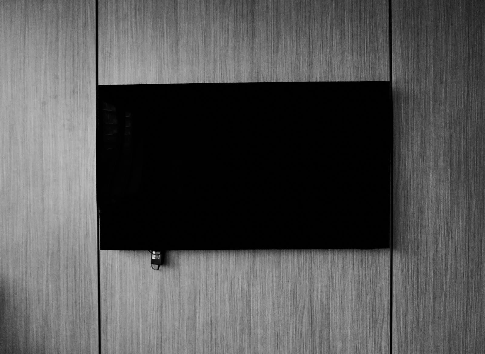 A television mounted on a wood-panelled wall